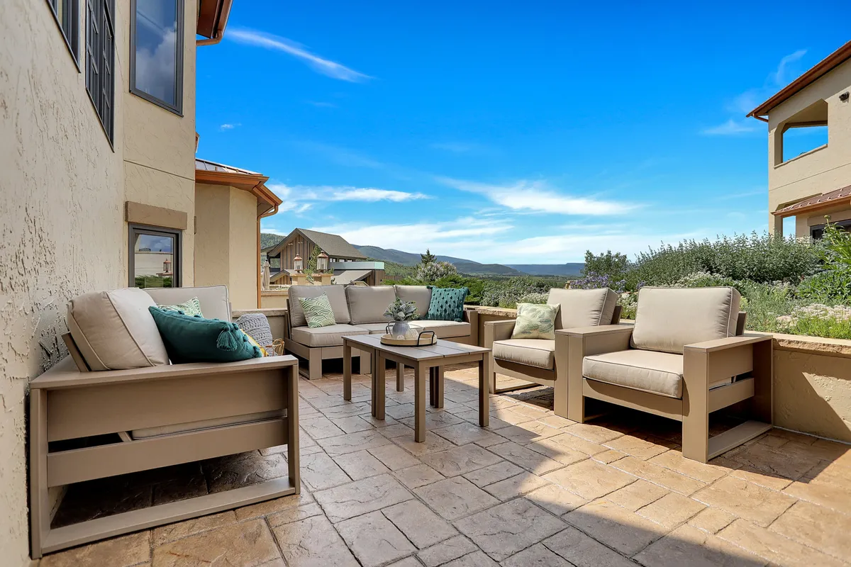 A serene outdoor seating area with a coffee table and distant mountains under a blue sky. The arrangement is designed for casual lounging, socializing, and enjoying nature's grandeur, perfectly aligned with the section's description of al fresco relaxation and panoramic views.