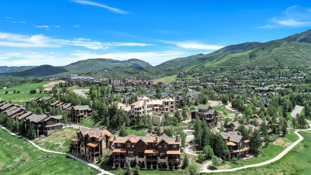 A serene exterior scene showing a mountain backdrop, abundant greenery, and elegant homes. The image suggests opportunities for outdoor activities such as hiking and biking, while conveying the welcoming atmosphere of the community.