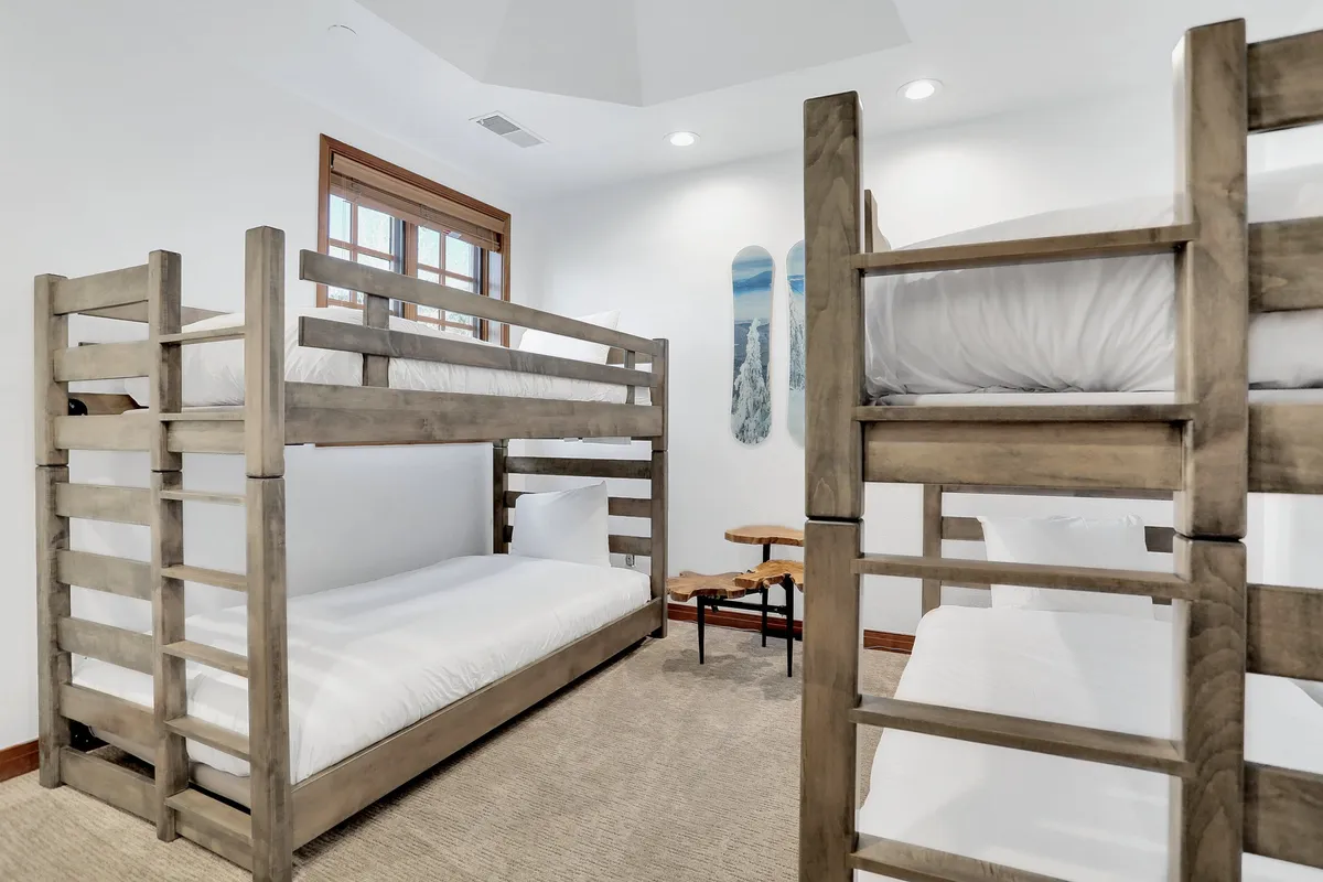 A playful bunk room designed for kids and teens, featuring sturdy wooden bunk beds, a cozy side table, and whimsical wall art. The mood is cheerful and welcoming, perfect for sleepovers and imaginative play.