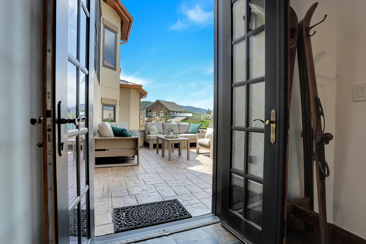 This exterior image features an open door leading to a welcoming outdoor seating area with a direct view of the mountains. The setting is ideal for socializing, relaxing, or simply enjoying nature, with the warm light suggesting comfort and exclusivity.