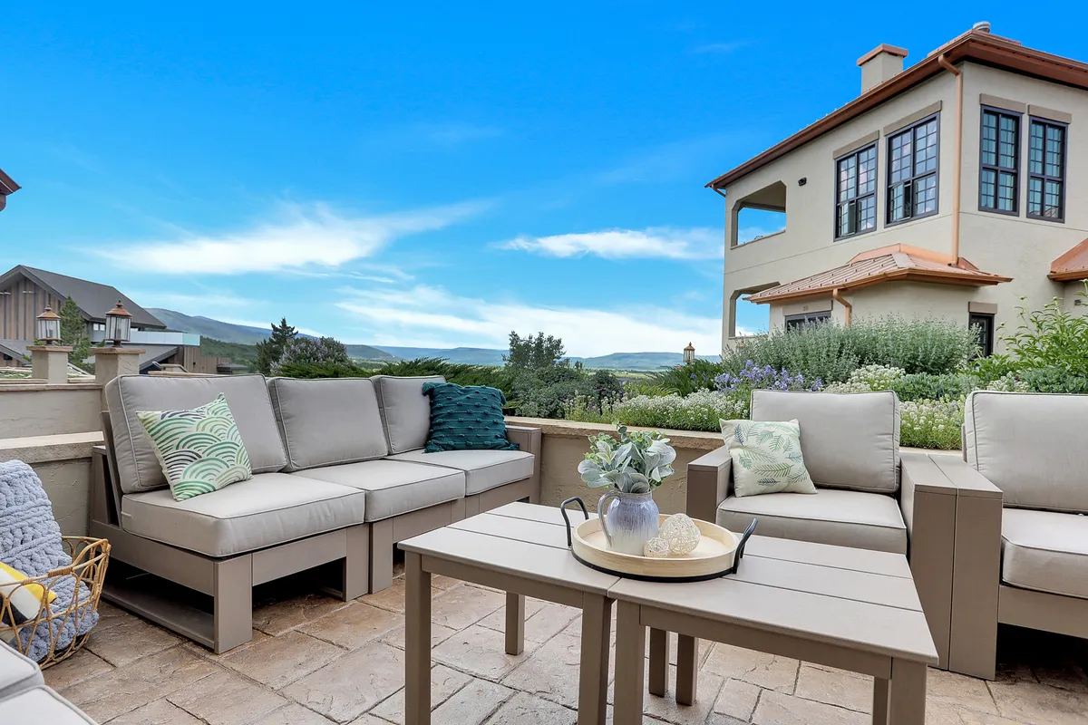 An inviting outdoor seating area set against a tranquil landscape, with decorative cushions, a table, and expansive views. The setting is ideal for relaxing, socializing, or simply soaking in the natural beauty after a day of exploration.
